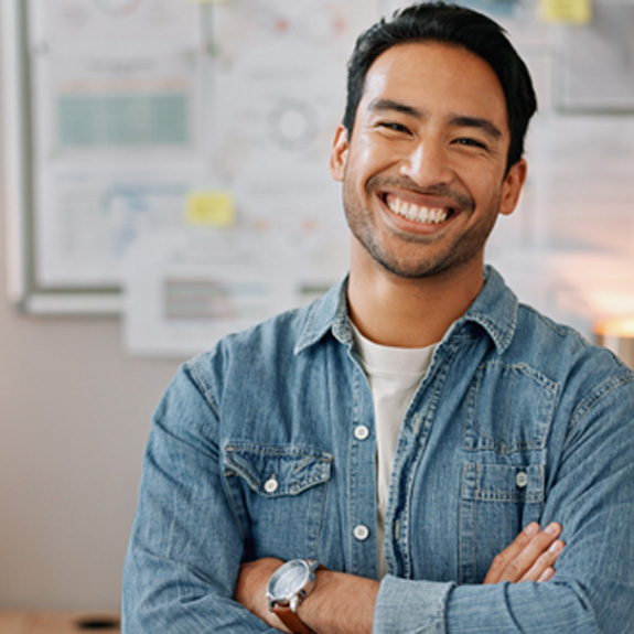 Man in denim shirt in office smiling