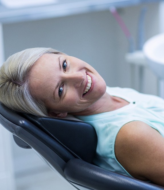 Woman leaning back in dental chair and smiling