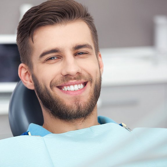 Bearded man sitting in dental chair and smiling