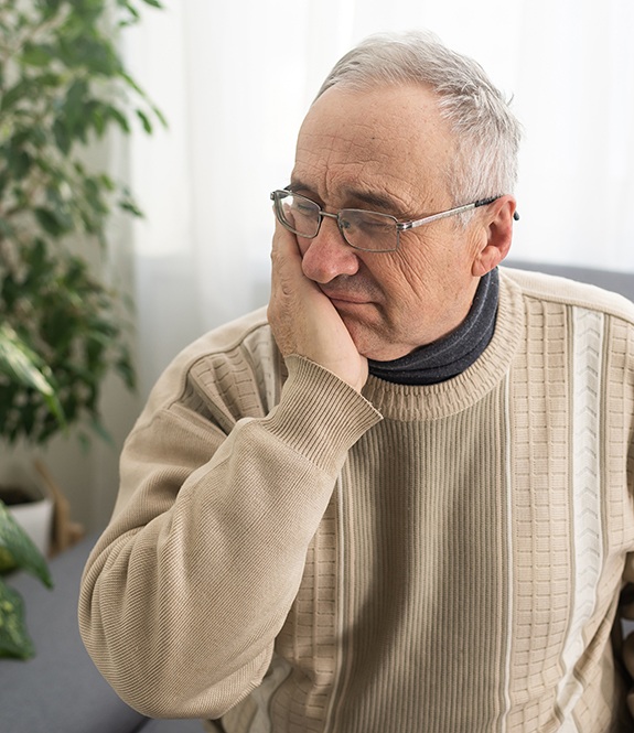 Senior man in sweater needing emergency dentist in Grand Prairie, TX