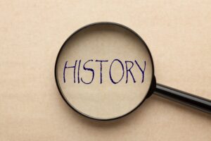 A magnifying glass covering the word "History" on parchment paper