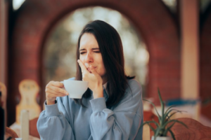 Woman trying to enjoy a hot drink but her teeth are sensitive 